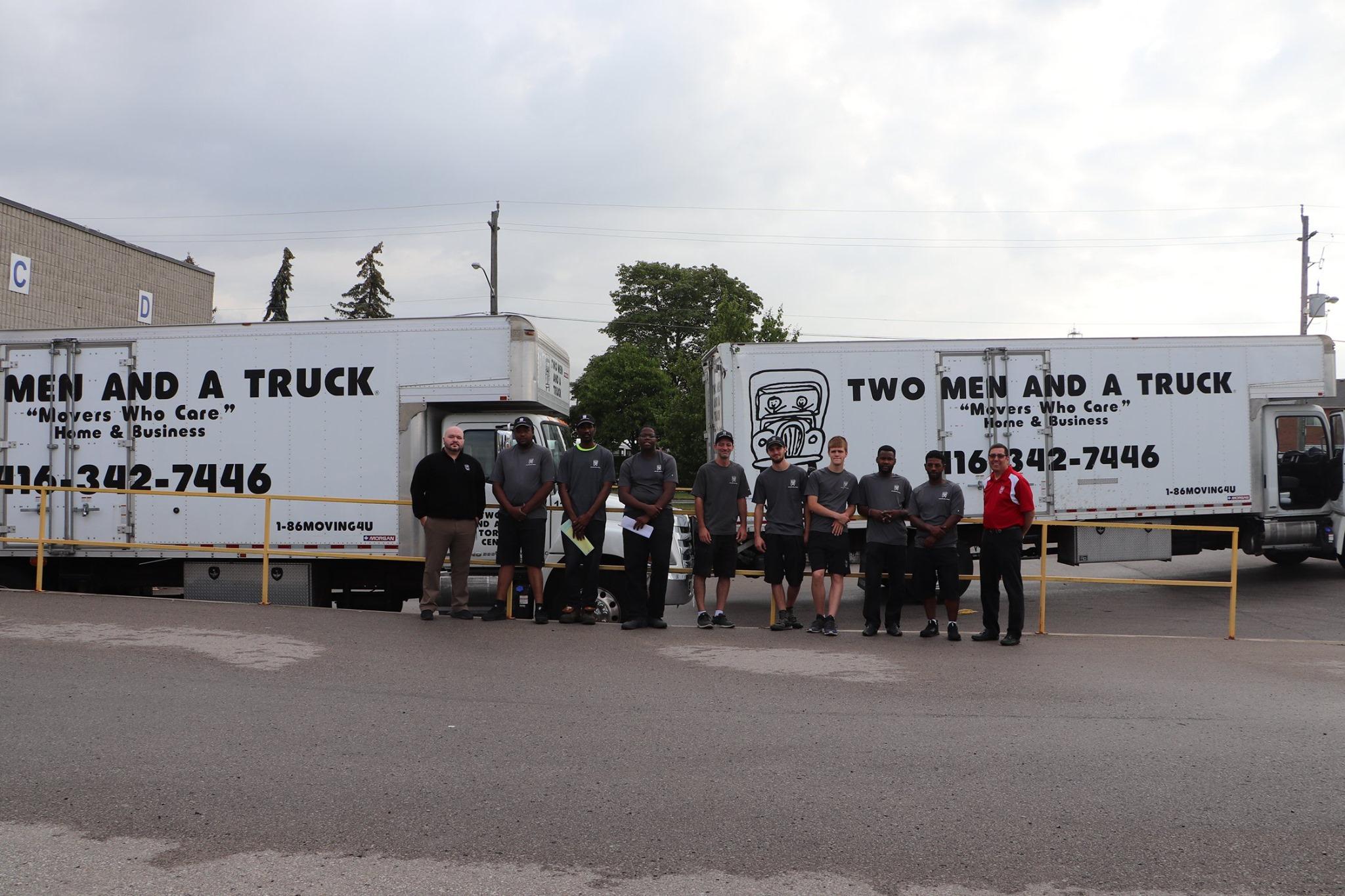 employees standing in front of two moving trucks