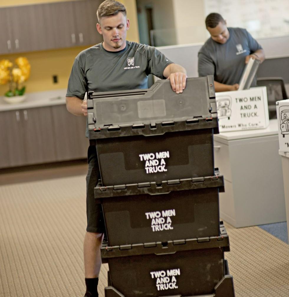 a mover pushing a dolly with two men and a truck branded boxes