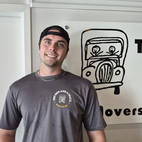 Mover standing in front of a Two Men and a Truck sign